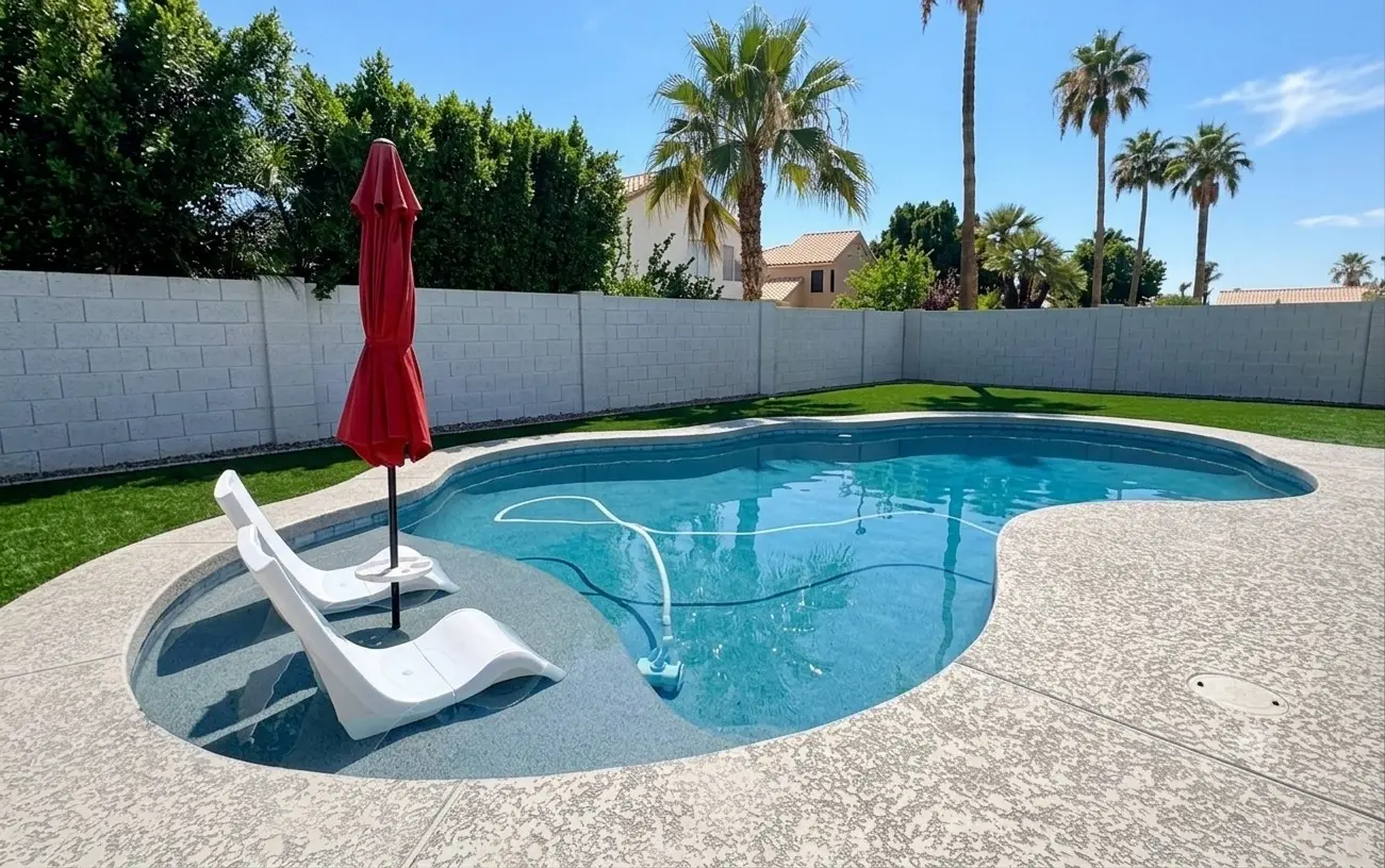 A crystal-clear freeform backyard pool with a tanning ledge